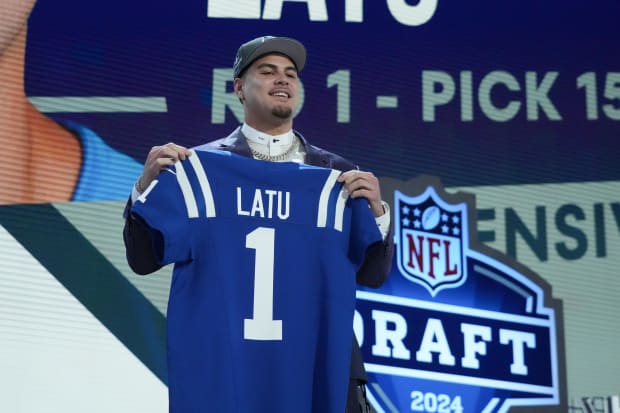 Football player Laiatu Latu stands with a blue Colts jersey at the NFL Draft.