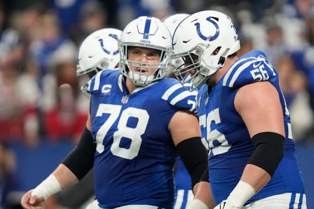 Football players Ryan Kelly and Quenton Nelson talk before a play in blue jerseys.