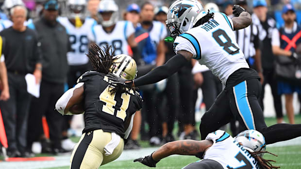 Saints running back Alvin Kamara (41) is tackled by Carolina Panthers cornerback Jaycee Horn (8) and linebacker Shaq Thompson