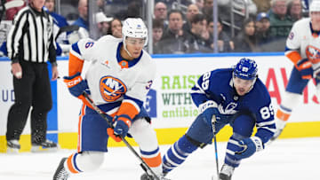 Dec 31, 2024; Toronto, Ontario, CAN; New York Islanders defenseman Isaiah George (36) skates with the puck as Toronto Maple Leafs left wing Nicholas Robertson (89) gives chase during the third period at the Scotiabank Arena. Mandatory Credit: Nick Turchiaro-Imagn Images
