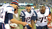 Nov 22, 2012; East Rutherford, NJ, USA; New England Patriots quarterback Tom Brady (12), safety Steve Gregory (28), and defensive tackle Vincent Wilfork (75) reach for a piece of a turkey while standing with NBC sports commentator Michele Tafoya after the game against the New York Jets on Thanksgiving at Metlife Stadium. The Patriots won the game 49-19. Mandatory Credit: Joe Camporeale-Imagn Images
