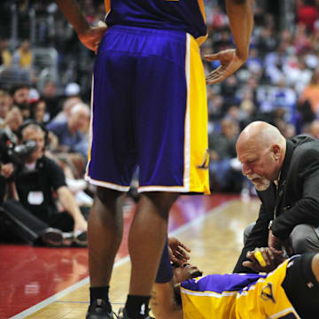 April 6, 2014; Los Angeles, CA, USA; Los Angeles Lakers trainer Gary Vitti looks at guard Kent Bazemore (6) after suffering an apparent injury in the first half at Staples Center. Mandatory Credit: Gary A. Vasquez-Imagn Images
