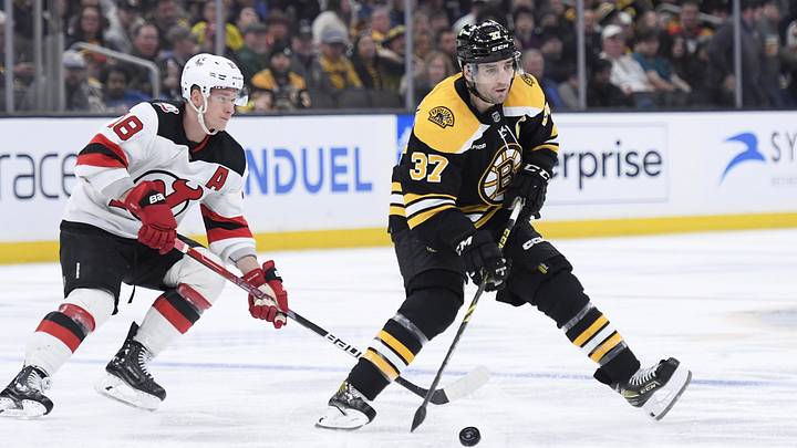 Apr 8, 2023; Boston, Massachusetts, USA;  Boston Bruins center Patrice Bergeron (37) controls the puck while New Jersey Devils left wing Ondrej Palat (18) defends during the third period at TD Garden. Mandatory Credit: Bob DeChiara-Imagn Images