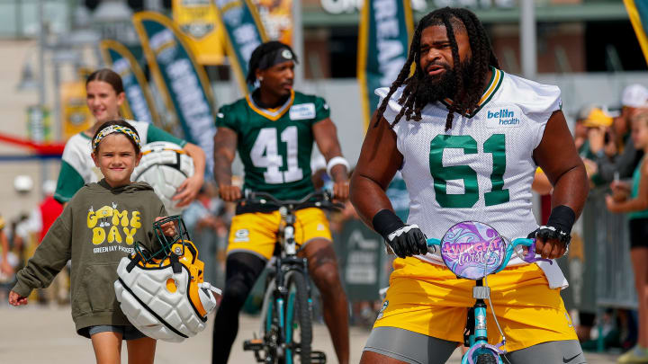 Green Bay Packers offensive lineman Lecitus Smith (61) rides a young fan’s bicycle to practice in the DreamDrive on Wednesday, July 24, 2024, at Lambeau Field in Green Bay, Wis. 
Tork Mason/USA TODAY NETWORK-Wisconsin