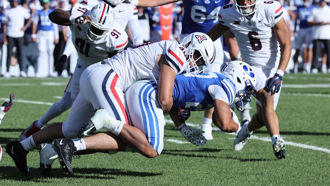 Oct 12, 2024; Provo, Utah, USA; Arizona Wildcats linebacker Lance Keneley (90) tackles Brigham Young Cougars running back LJ Martin (27) during the third quarter at LaVell Edwards Stadium. Mandatory Credit: Rob Gray-Imagn Images