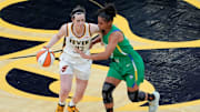 Caitlin Clark brings the ball up court as Brazil's Carina Dos Santos Martins defends her.