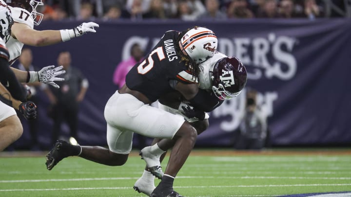 Dec 27, 2023; Houston, TX, USA; Oklahoma State Cowboys safety Kendal Daniels (5) tackles Texas A&M Aggies running back Rueben Owens (2) during the first quarter at NRG Stadium. Mandatory Credit: Troy Taormina-USA TODAY Sports