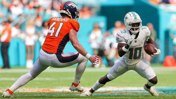 Miami Dolphins wide receiver Tyreek Hill (10) runs with the ball defended by Denver Broncos linebacker Drew Sanders (41).