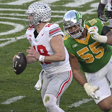 Jan 1, 2025; Pasadena, CA, USA;  Ohio State Buckeyes quarterback Will Howard (18) looks for an open receiver as Oregon Ducks defensive lineman Derrick Harmon (55) closes in durigt the third quarter at Rose Bowl Stadium. Mandatory Credit: Robert Hanashiro-Imagn Images