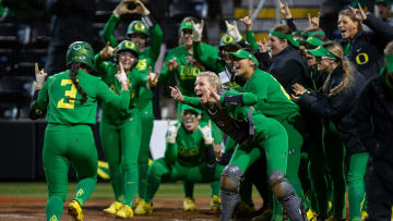 Oregon players gather at home plate to celebrate a home run by Oregon outfielder Ariel Carlson, left, during a win over Oregon State at Jane Sanders Stadium on Saturday, April 30, 2022.