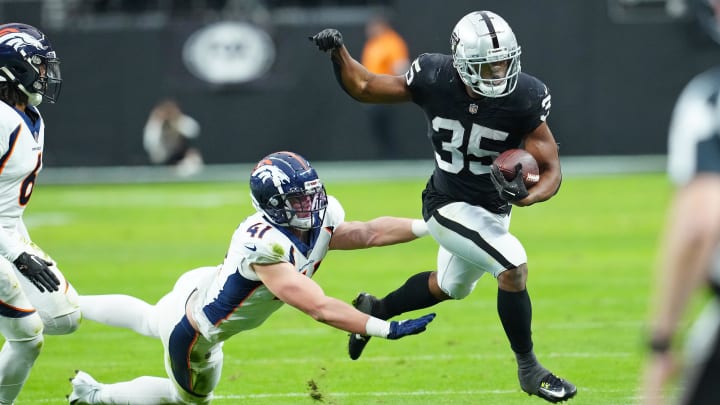 Jan 7, 2024; Paradise, Nevada, USA; Las Vegas Raiders running back Zamir White (35) is pushed out of bounds by Denver Broncos linebacker Drew Sanders (41) during the second quarter at Allegiant Stadium. Mandatory Credit: Stephen R. Sylvanie-USA TODAY Sports