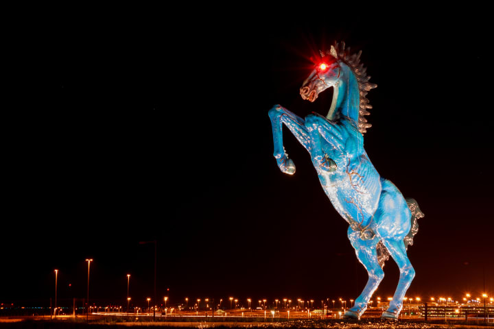 a massive blue fiberglass mustang, with glowing red eyes, standing on its hind legs