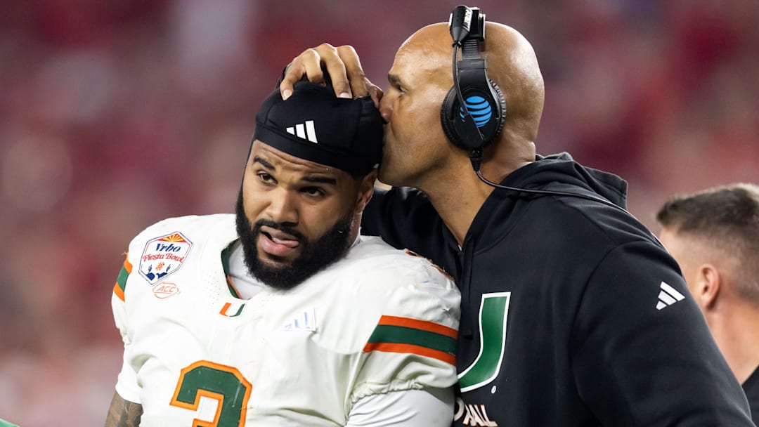 Jan 8, 2026; Glendale, AZ, USA; Miami Hurricanes defensive line coach Jason Taylor kisses the head of defensive lineman Akheem Mesidor (3) after suffering an injury against the Mississippi Rebels during the 2026 Fiesta Bowl and semifinal game of the College Football Playoff at State Farm Stadium. Mandatory Credit: Mark J. Rebilas-Imagn Images