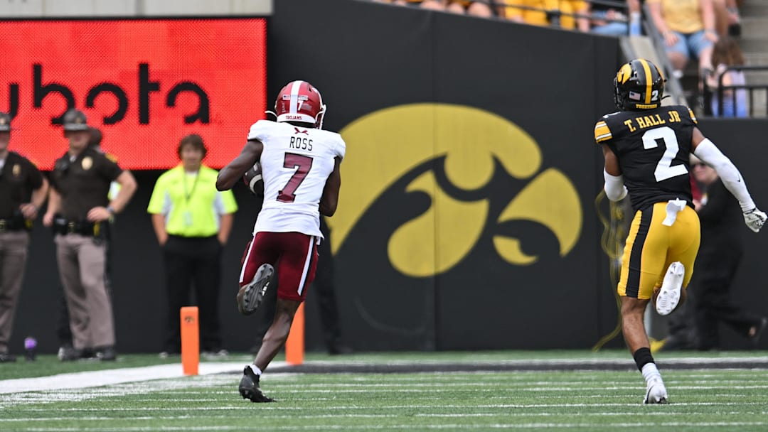 Sep 14, 2024; Iowa City, Iowa, USA; Troy Trojans wide receiver Devonte Ross (7) catches a 63 yard touchdown pass from quarterback Matthew Caldwell (not pictured) as Iowa Hawkeyes defensive back TJ Hall (2) pursues during the second quarter at Kinnick Stadium. Mandatory Credit: Jeffrey Becker-Imagn Images