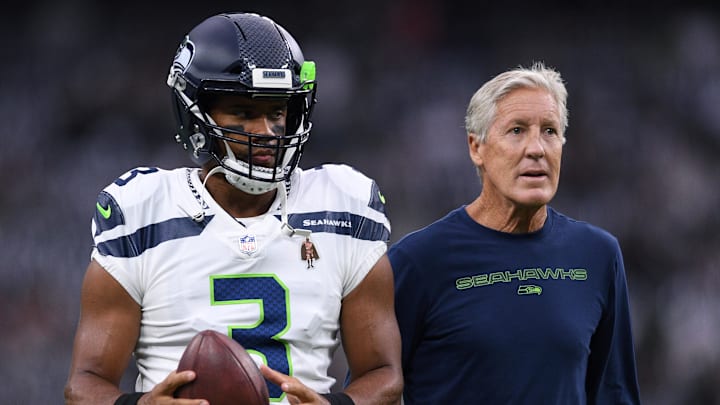 Former Seattle Seahawks quarterback Russell Wilson warms up for a game in 2021 beside coach Pete Carroll.