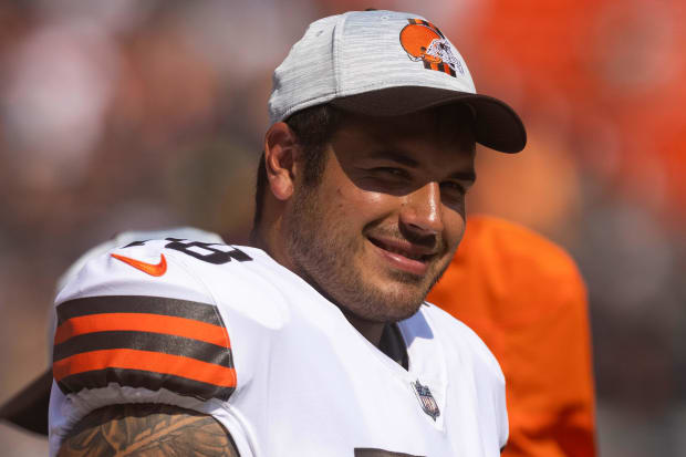 Offensive lineman smiles on sideline with helmet off.