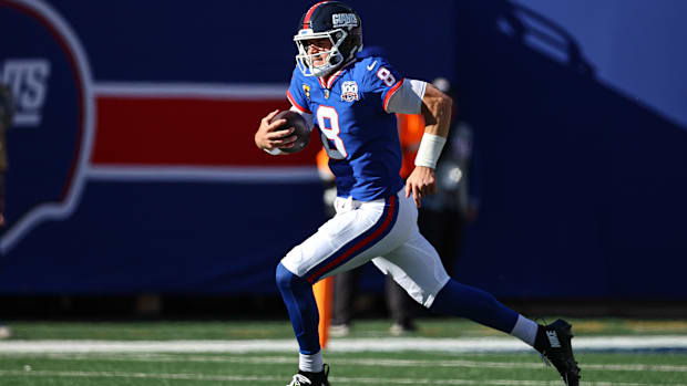 Colts quarterback Daniel Jones (blue jersey) runs with the football to gain yards.