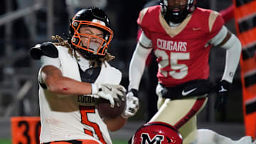 Cocoa High wide receiver Jayvan Boggs (#5) is pulled down by a Cardinal Mooney defender. Cocoa High School defeated Cardinal Mooney Catholic High School 31-21 to win the Class 2A semi-final game Friday night in Sarasota.