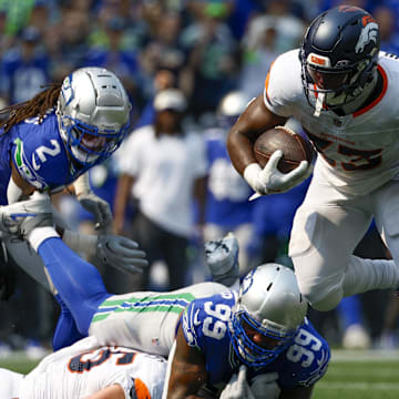 Sep 8, 2024; Seattle, Washington, USA; Denver Broncos running back Javonte Williams (33) breaks a tackle attempt by Seattle Seahawks defensive end Leonard Williams (99) during the second quarter at Lumen Field.  Images