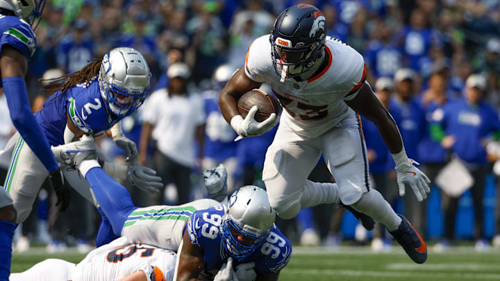 Sep 8, 2024; Seattle, Washington, USA; Denver Broncos running back Javonte Williams (33) breaks a tackle attempt by Seattle Seahawks defensive end Leonard Williams (99) during the second quarter at Lumen Field.  Images