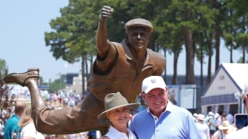 Spectators pose for photos in front of a statue of late golfer Payne Stewart during the third round of the U.S. Open golf tournament.