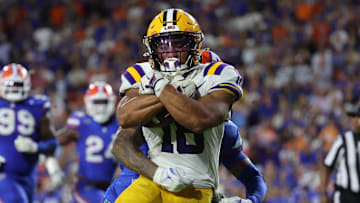 Nov 16, 2024; Gainesville, Florida, USA; LSU Tigers running back Josh Williams (18) runs with the ball as Florida Gators defensive back Sharif Denson (0) tackles during the second half at Ben Hill Griffin Stadium. Mandatory Credit: Kim Klement Neitzel-Imagn Images