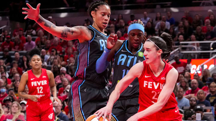 Indiana Fever guard Caitlin Clark (22) passes around Atlanta Dream guard Rhyne Howard (10) and Atlanta Dream center Brittney Griner (42) on Friday, July 11, 2025, during a game between the Indiana Fever and the Atlanta Dream at Gainbridge Fieldhouse in Indianapolis.