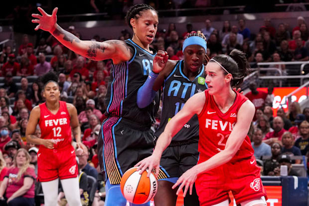 Indiana Fever guard Caitlin Clark (22) passes around Atlanta Dream guard Rhyne Howard (10) and center Brittney Griner (42).