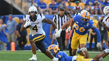 Sep 14, 2024; Pittsburgh, Pennsylvania, USA; West Virginia Mountaineers running back CJ Donaldson Jr. (4) breaks a tackle attempt by Pittsburgh Panthers linebacker Braylon Lovelace (on ground) in the second quarter at Acrisure Stadium. Mandatory Credit: Barry Reeger-Image Images
