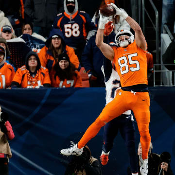 Dec 24, 2023; Denver, Colorado, USA; Denver Broncos tight end Lucas Krull (85) makes a catch for a touchdown under pressure from New England Patriots cornerback Myles Bryant (27) as linebacker Ja'Whaun Bentley (8) defends in the fourth quarter at Empower Field at Mile High. Mandatory Credit: Isaiah J. Downing-USA TODAY Sports