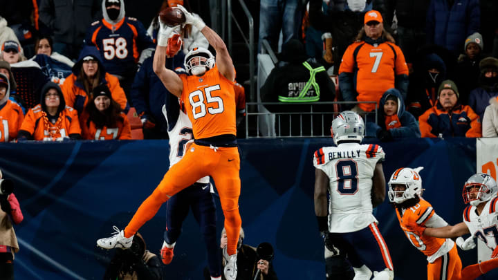 Dec 24, 2023; Denver, Colorado, USA; Denver Broncos tight end Lucas Krull (85) makes a catch for a touchdown under pressure from New England Patriots cornerback Myles Bryant (27) as linebacker Ja'Whaun Bentley (8) defends in the fourth quarter at Empower Field at Mile High. Mandatory Credit: Isaiah J. Downing-USA TODAY Sports