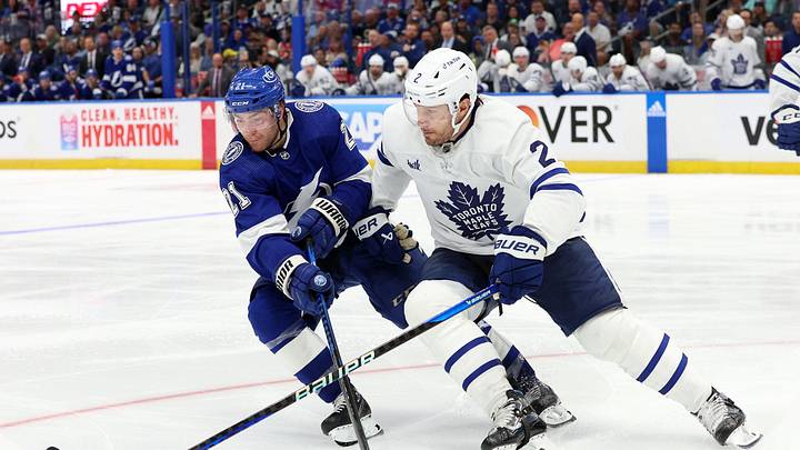 Apr 22, 2023; Tampa, Florida, USA; Tampa Bay Lightning center Brayden Point (21) and Toronto Maple Leafs defenseman Luke Schenn (2) battle for the puck during the third period in game three of the first round of the 2023 Stanley Cup Playoffs at Amalie Arena. Mandatory Credit: Kim Klement-Imagn Images