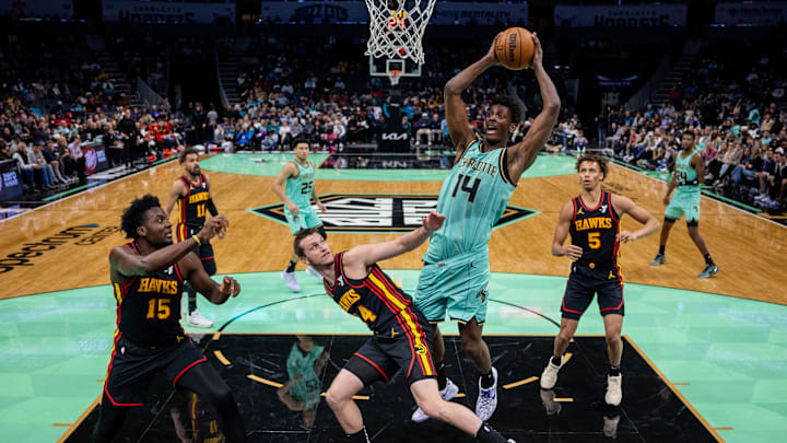 Nov 30, 2024; Charlotte, North Carolina, USA; Charlotte Hornets forward Moussa Diabaté (14) grabs a rebound over Atlanta Hawks guard Garrison Mathews (24) during the first quarter at Spectrum Center. Mandatory Credit: Scott Kinser-Imagn Images