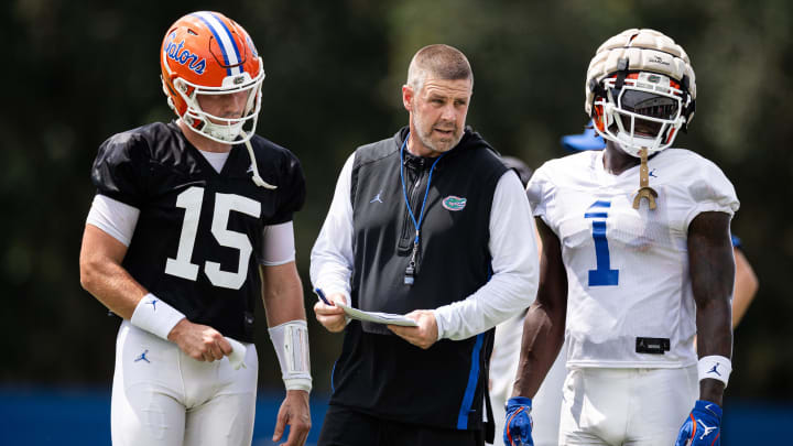 Florida Gators head coach Billy Napier talks with Florida Gators quarterback Graham Mertz (15) and Florida Gators running back Montrell Johnson Jr. (1) during fall football practice at Heavener Football Complex at the University of Florida in Gainesville, FL on Thursday, August 1, 2024