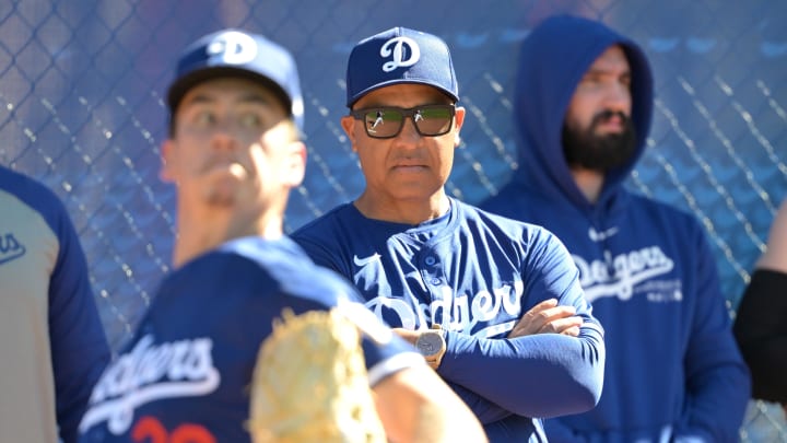 Feb 18, 2024; Glendale, AZ, USA; Los Angeles Dodgers manager Dave Roberts (30) looks on as starting pitcher Bobby Miller (28) throws in the bullpen during spring training at Camelback Ranch.  Mandatory Credit: Jayne Kamin-Oncea-USA TODAY Sports