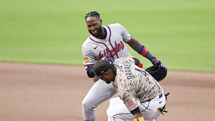 Mar 30, 2025; San Diego, California, USA; Atlanta Braves left fielder Jurickson Profar (7) helps San Diego Padres first baseman Luis Arraez (4) up after grounding out during the seventh inning at Petco Park. Mandatory Credit: Denis Poroy-Imagn Images