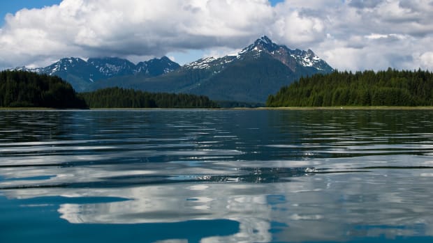 A stunning mountain scene in the background with water in the front.