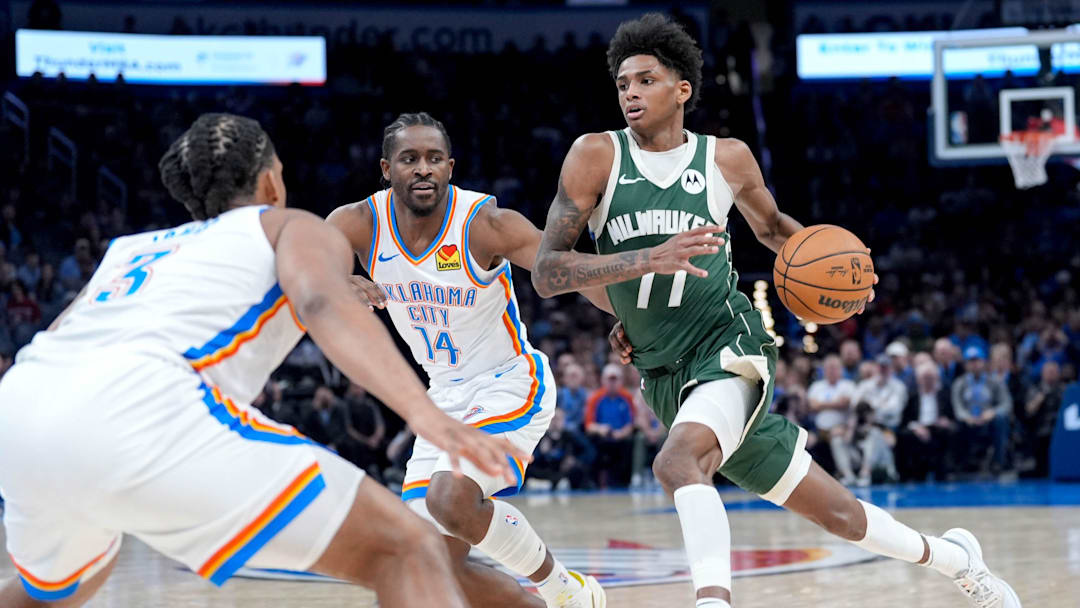 Milwaukee guard AJ Johnson (77) drives forward past Oklahoma City forward Adam Flagler (14) and Oklahoma City forward Dillon Jones (3) in the fourth quarter during an NBA game between Oklahoma City and Milwaukee at the Paycom Center in Oklahoma City on Monday, Feb. 3, 2025.