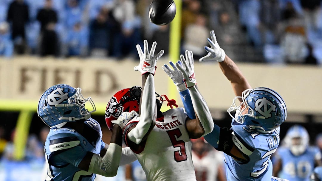 Nov 30, 2024; Chapel Hill, North Carolina, USA; North Carolina State Wolfpack wide receiver Noah Rogers (5) catches a 44 yard pass as North Carolina Tar Heels defensive backs Marcus Allen (29) and Will Hardy (31) defend in the fourth quarter at Kenan Memorial Stadium. Mandatory Credit: Bob Donnan-Imagn Images