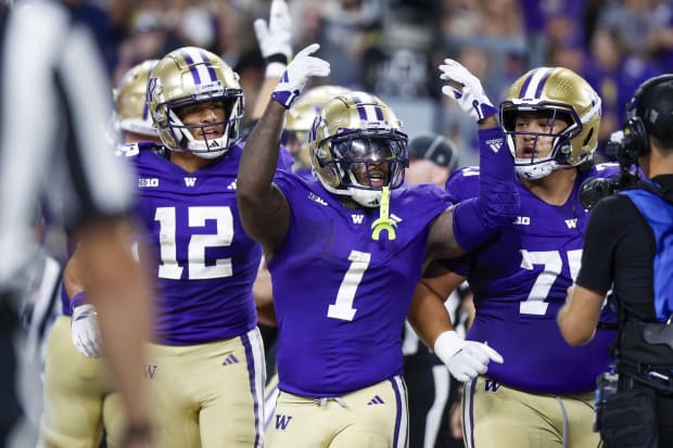 Huskies running back Jonah Coleman (1) celebrates with wide receiver Denzel Boston (12) and center D'Angalo Titialii (75) aft