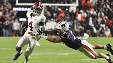 Nov 25, 2023; Auburn, Alabama, USA;  Auburn Tigers linebacker Larry Nixon III (30) shoves Alabama Crimson Tide quarterback Jalen Milroe (4) toward the sidelines at Jordan-Hare Stadium. Alabama won 27-24. Mandatory Credit: Gary Cosby Jr.-Imagn Images