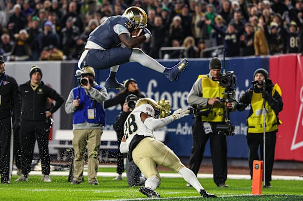Notre Dame Fighting Irish running back Jeremiyah Love leaps over Army's  Donavon Platt for a touchdown.