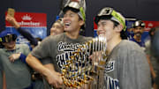 Oct 31, 2025; Toronto, Ontario, CAN; Los Angeles Dodgers two-way player Shohei Ohtani (17) and pitcher Yoshinobu Yamamoto (18) and pitcher Roki Sasaki (11) celebrate with the Commissioner's Trophy in the clubhouse after defeating the Toronto Blue Jays in the 2025 MLB World Series at Rogers Centre. Mandatory Credit: John E. Sokolowski-Imagn Images