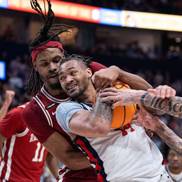 Arkansas Razorbacks forward Jonas Aidoo (9) guards Ole Miss Rebels guard Dre Davis (14) while Arkansas Razorbacks guard Trevon Brazile (4) defends during their second round game of the SEC Men's Basketball Tournament at Bridgestone Arena in Nashville.