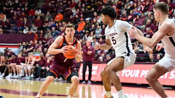 Feb 15, 2025; Blacksburg, Virginia, USA; Virginia Tech Hokies guard Brandon Rechsteiner (7) controls the ball as Virginia Cavaliers forward Jacob Cofie (5) defends during the first half at Cassell Coliseum. Mandatory Credit: Brian Bishop-Imagn Images