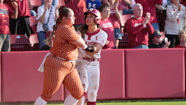 Texas' Mac Morgan (55) pushes past Oklahoma's Nelly McEnroe-Marinas (2) in the fifth inning during the college softball game 