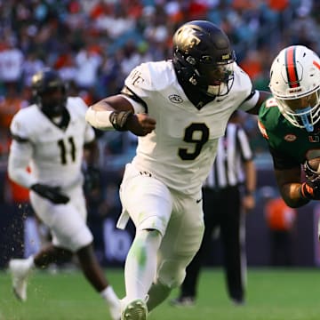 Nov 23, 2024; Miami Gardens, Florida, USA; Miami Hurricanes tight end Elijah Arroyo (8) runs with the football as Wake Forest Demon Deacons linebacker Quincy Bryant (9) attempts a tackle during the second quarter at Hard Rock Stadium. 