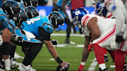 Nov 10, 2024; Munich, Germany; Helmets at the line of scrimmage as Carolina Panthers guard Cade Mays (64) snaps the ball against the New York Giants in the first half during the 2024 NFL Munich Game at Allianz Arena. 