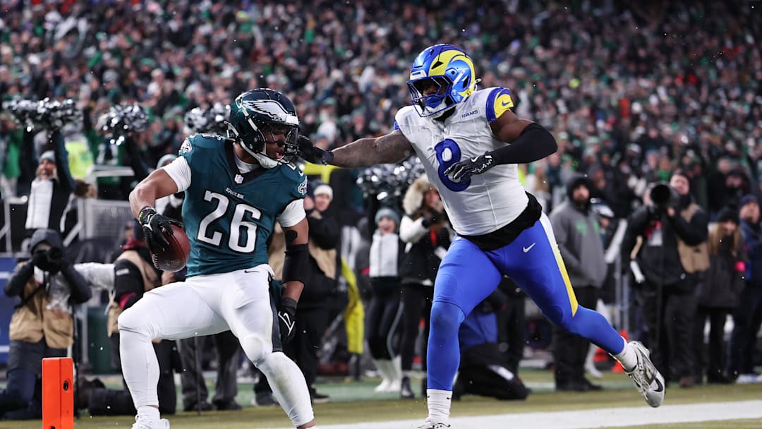 Jan 19, 2025; Philadelphia, Pennsylvania, USA; Philadelphia Eagles running back Saquon Barkley (26) scores a touchdown past Los Angeles Rams linebacker Jared Verse (8) in the first half in a 2025 NFC divisional round game at Lincoln Financial Field. Mandatory Credit: Bill Streicher-Imagn Images