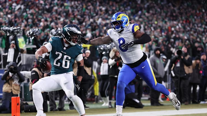 Jan 19, 2025; Philadelphia, Pennsylvania, USA; Philadelphia Eagles running back Saquon Barkley (26) scores a touchdown past Los Angeles Rams linebacker Jared Verse (8) in the first half in a 2025 NFC divisional round game at Lincoln Financial Field. Mandatory Credit: Bill Streicher-Imagn Images